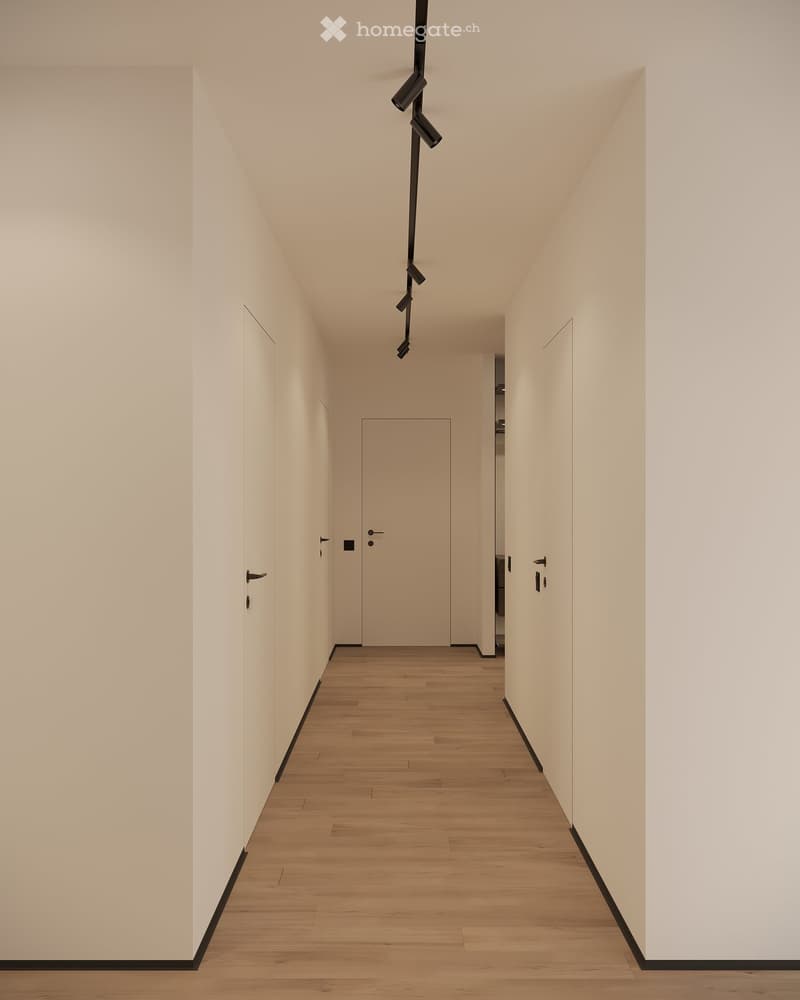Empty hallway with white walls, wooden floor, and black trims, with three spotlights on the ceiling
