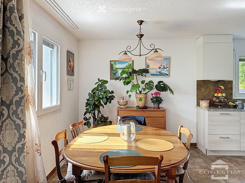 Dining room with wooden table, chairs, plants, and a chandelier