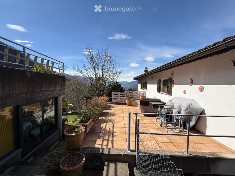 Terraced house with a terrace, tiled floor, metal railings, potted plants, and a view of the mountains.