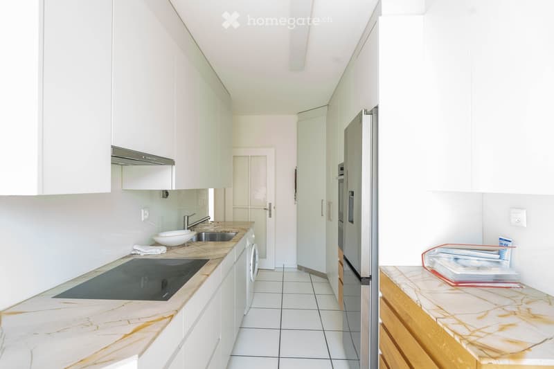 modern kitchen with marble countertops, stainless steel appliances, white cabinets, induction cooktop, sink, and washing machine