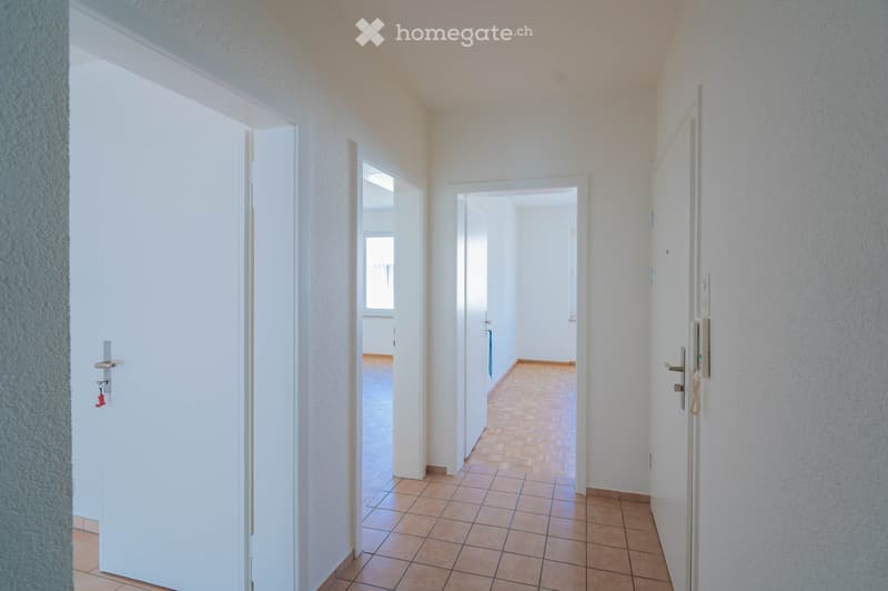 Empty hallway with tiled floor, white walls, and doors