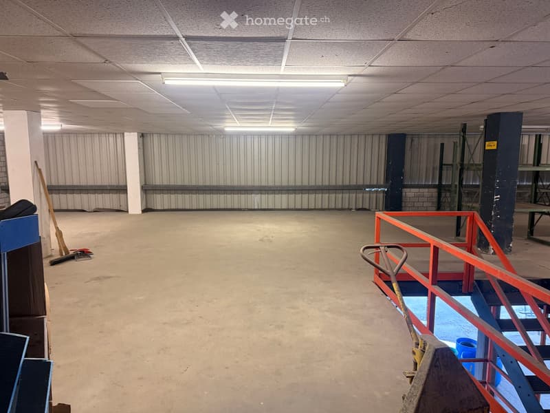 Empty room with metal walls, concrete floor, metal railings, and a broom