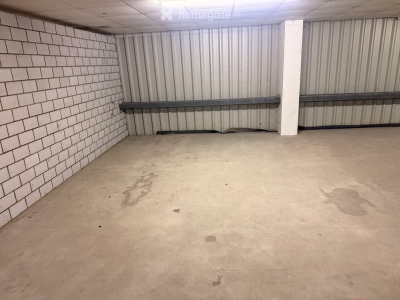 Empty room with white brick wall, metal wall, concrete floor, and a metal beam