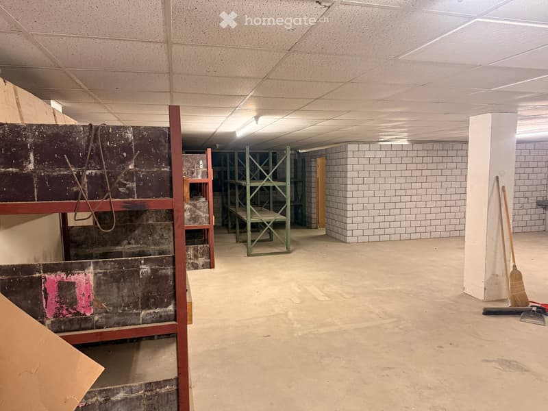 Empty room with white brick wall, metal shelves, and cleaning tools