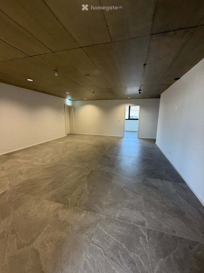 Empty room with gray tiled floor, white walls, two doors, and ceiling lights