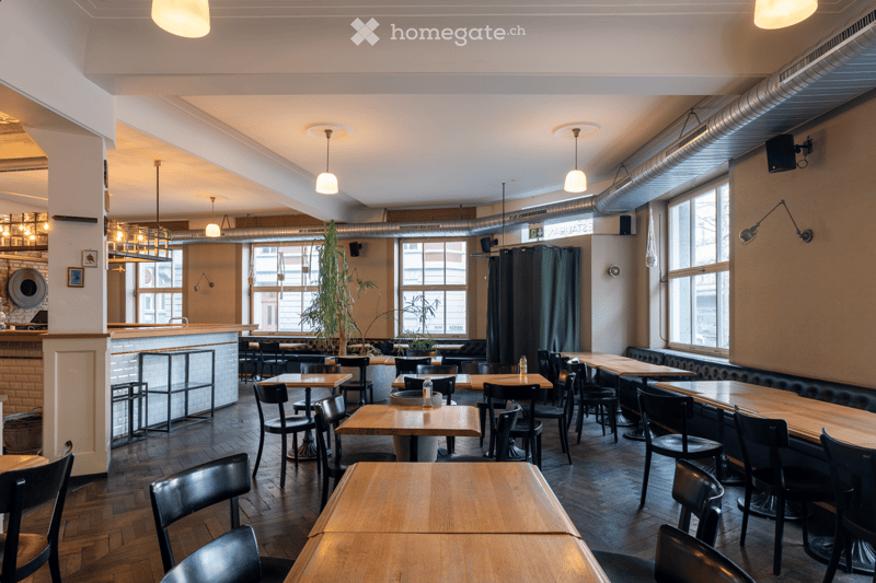 wooden tables, black chairs, white walls, large windows, wooden floor, bar counter, plants