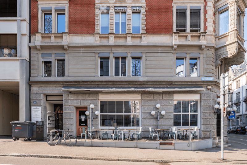 3 story building, brick facade, large windows, outdoor seating area, bicycle parked