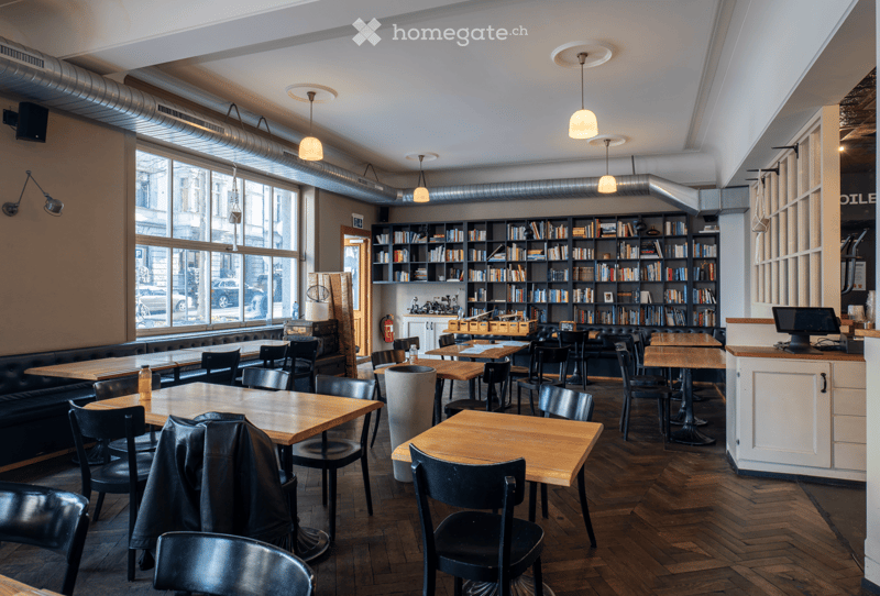 wooden tables, black chairs, bookshelves, large windows, wooden floor, lamps