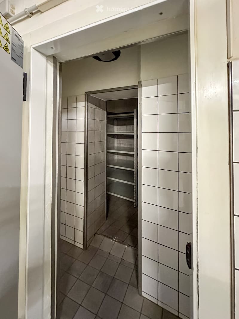 tiled floor, tiled walls, open door, metal shelves, empty room