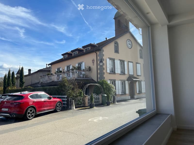 large building, beige exterior, clock, balcony, red car parked in front