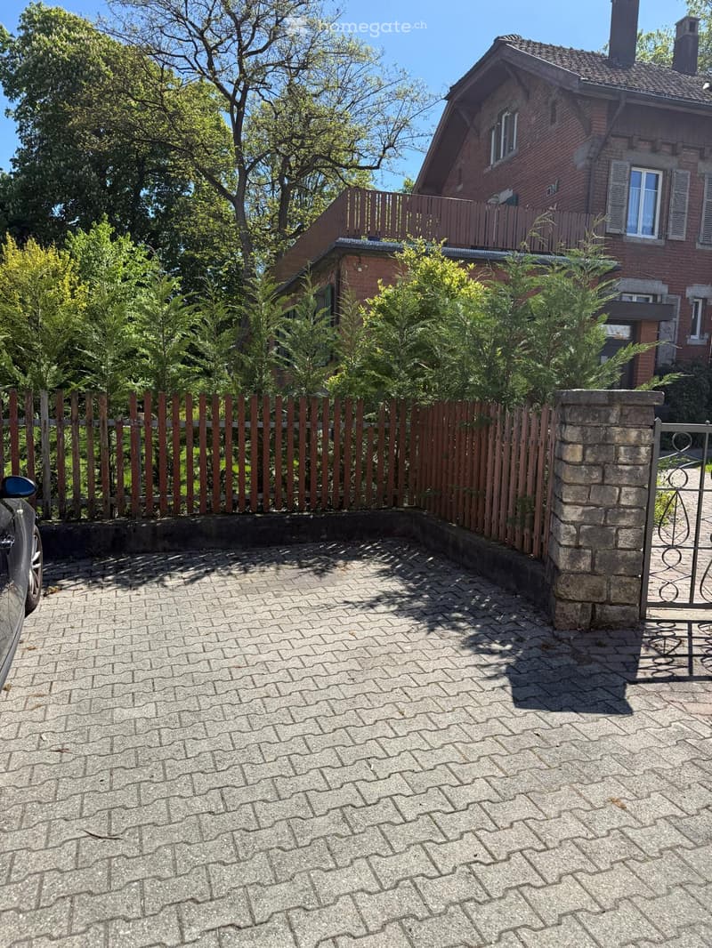 brick house, wooden fence, paved parking area, gate, car parked