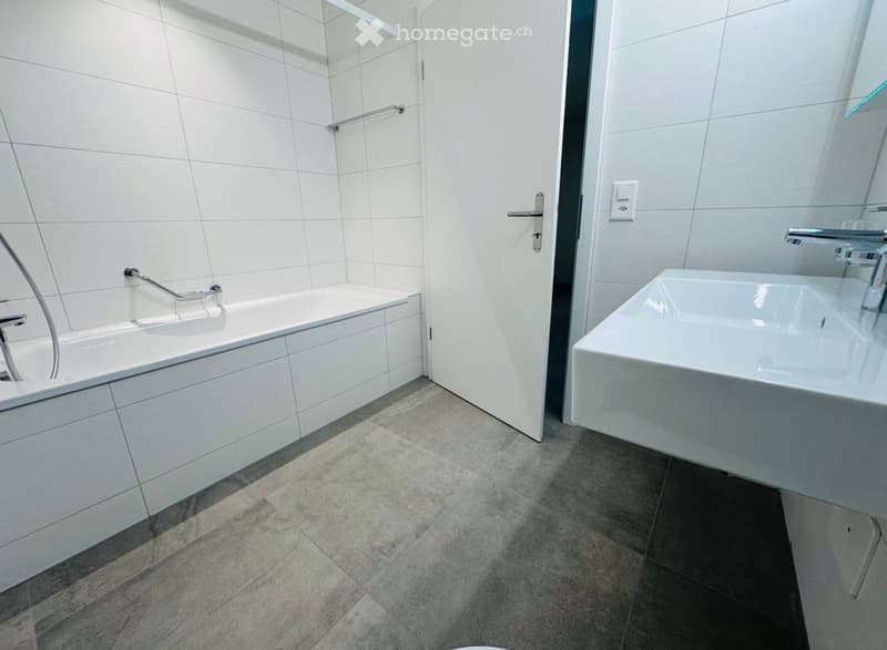 modern bathroom with white tiles, bathtub, sink, and shower