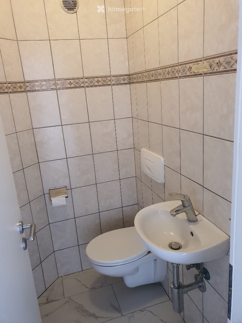 Bathroom. Small bathroom with white tiles, a toilet, a sink, and a wall-mounted soap dispenser.