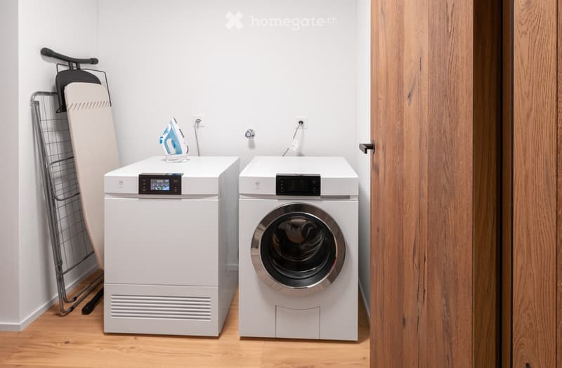 Laundry room with white appliances, hardwood flooring, and white walls