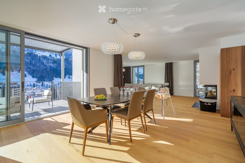 Wooden flooring, open sliding glass doors, modern chandeliers, dining table with chairs, balcony with table and chairs, view of mountains