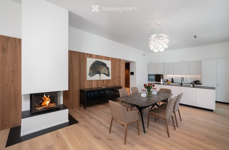 Wooden floor, white walls, black fireplace, dining table, white cabinet, chandelier, sink