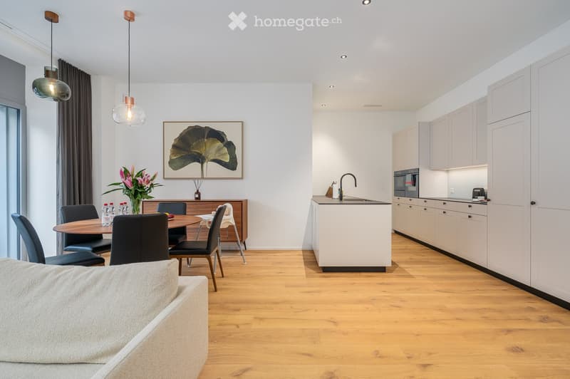 modern interior design, wooden floor, dining table with 4 chairs, white cabinets, kitchen area with modern appliances, couch, wooden pendant lights