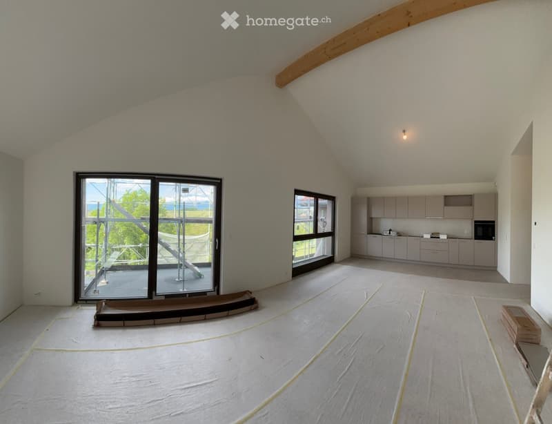 Furnished Room. Open-plan space with exposed wooden beams, large windows, and a fitted kitchen area with cabinets and an oven. The floor is covered with protective sheeting.