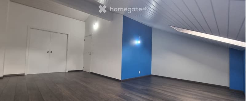 Empty room with white walls, dark wooden floor, and two doors.