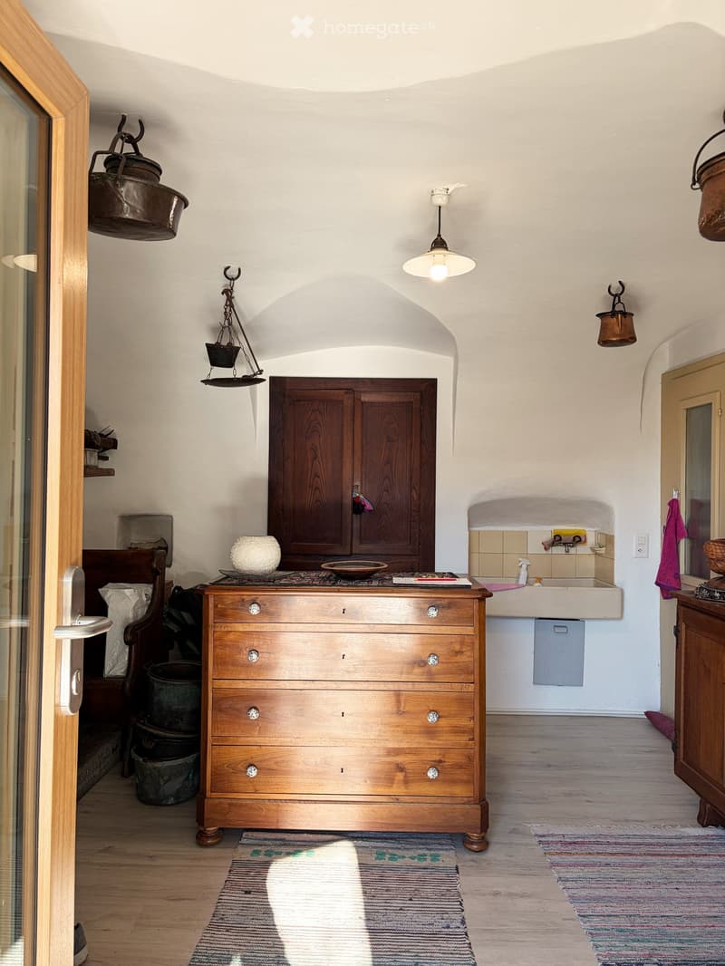 A room with a wooden cabinet, sink, and an antique lamp.