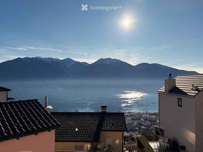 Building with a view over mountains, city, and water