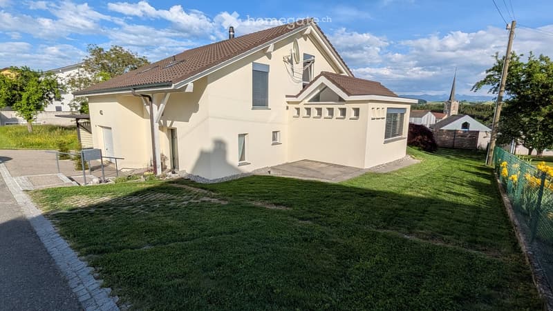 House. Two-story house with beige exterior, brown tiled roof, multiple windows, and a well-maintained lawn in front.