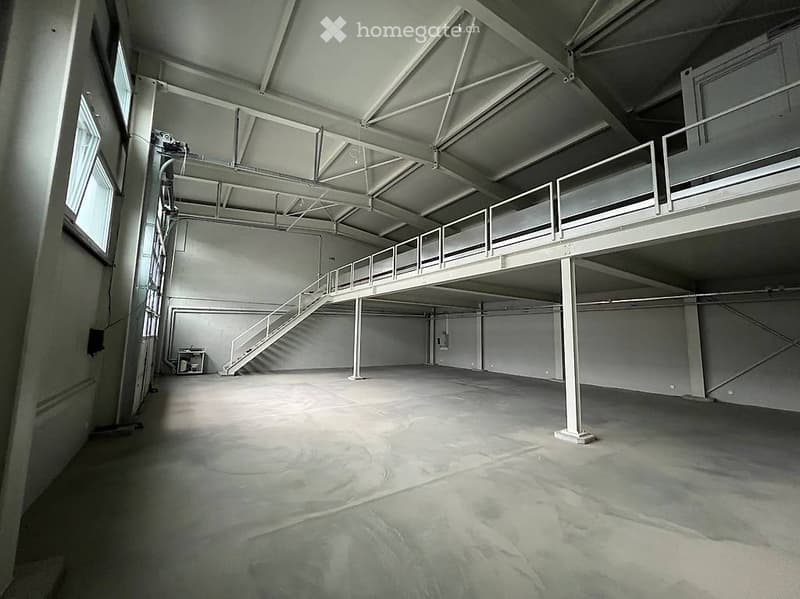 Unfurnished Room. Large, empty industrial-style space with concrete floor, metal beams, and a metal staircase leading to an upper level. No furniture or equipment present.