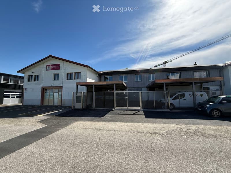 Building. Two-story building with a garage, fenced parking area, and a sign on the wall.