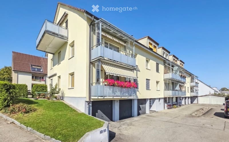 3 story apartment building, yellow exterior, balconies, parking area, green lawn