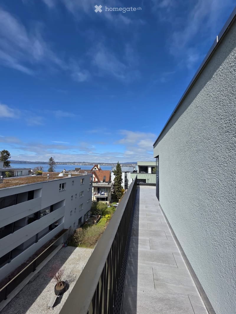 Balcony / Terrace. Balcony overlooking a residential area with buildings, greenery, and a body of water in the distance.