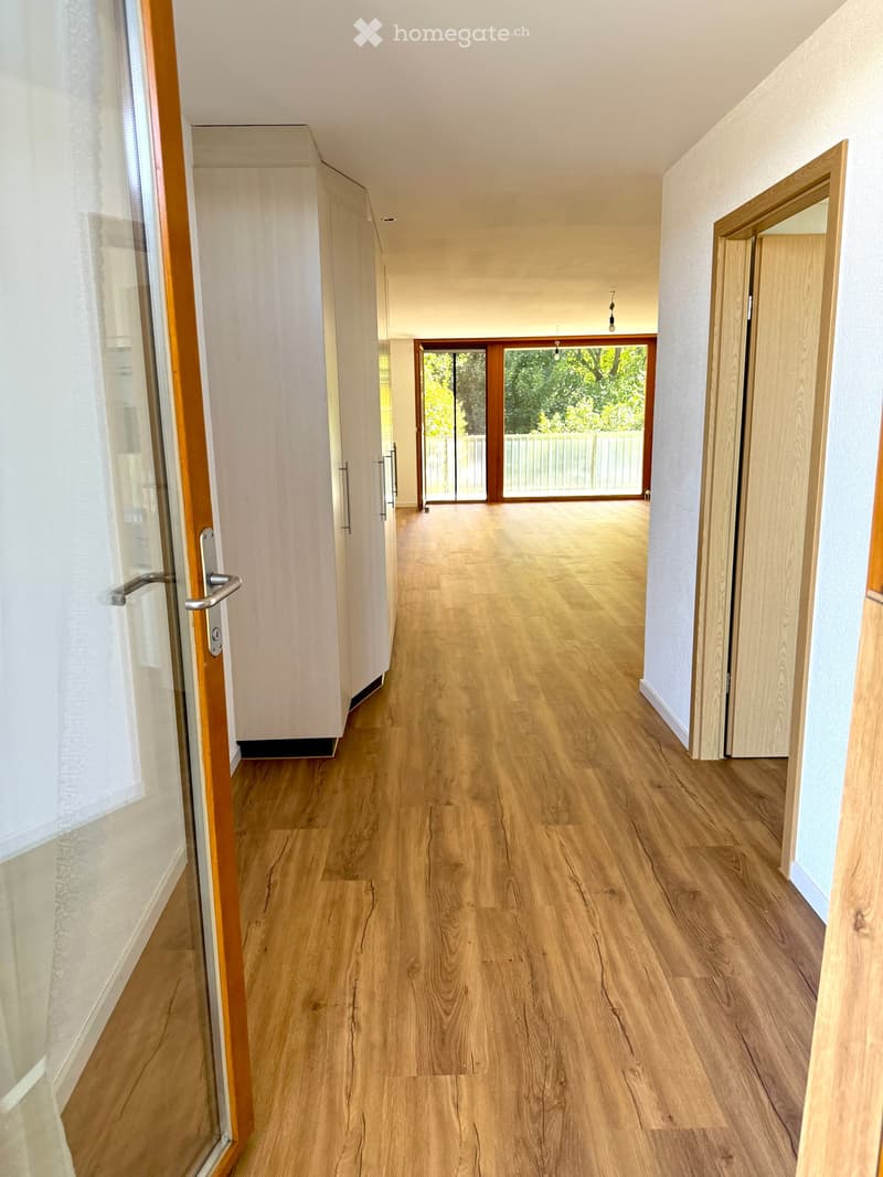 large hallway with wooden floors, glass sliding doors, tall windows with balconies