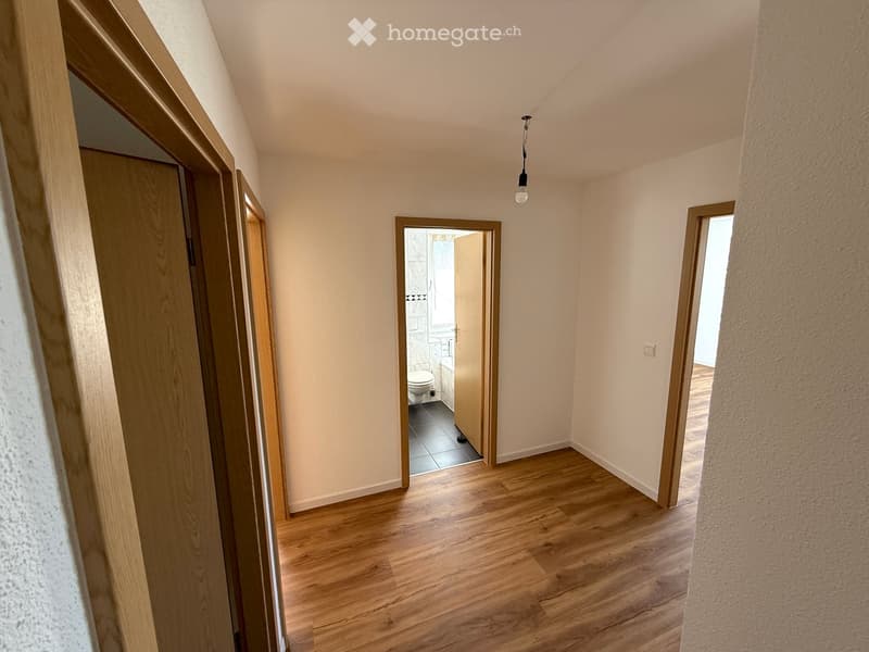 Wooden floors, white walls, light fixture, door leading to bathroom