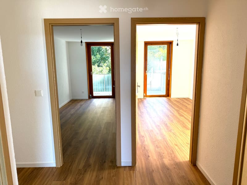 Open room with wooden floor and sliding glass doors leading to balcony