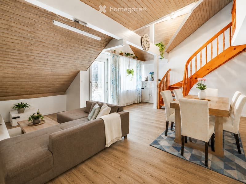 Bright living and dining area with wooden floors, a curved staircase, and modern furnishings including a sofa, coffee table, dining table, and chairs.