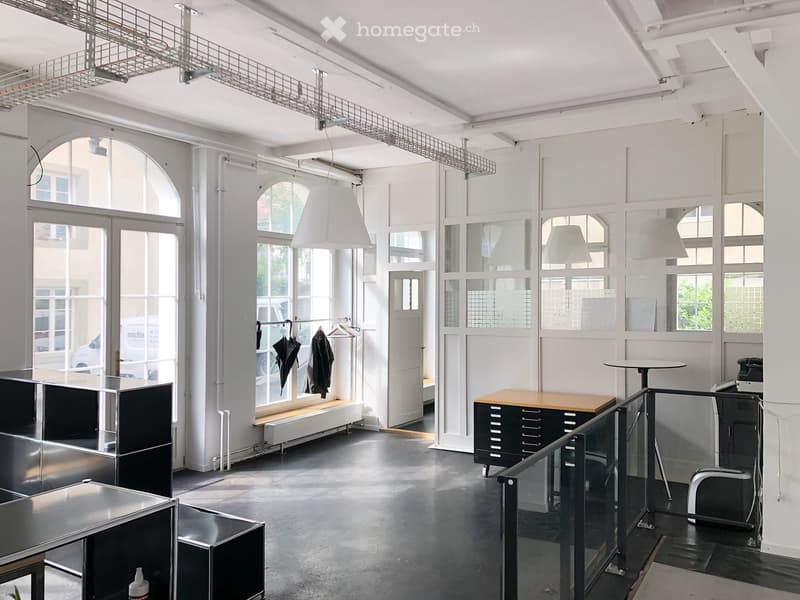 Modern, minimalist room with large windows, industrial-style lighting, and a mix of metallic and wooden furniture.
