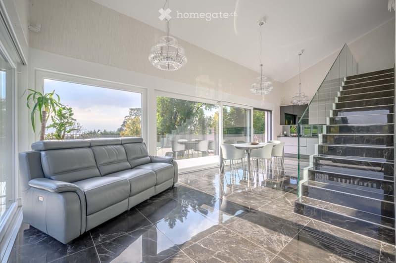 Living Room. Spacious living room with a large leather sofa, dining table, and glass walls offering a view of the outdoors.