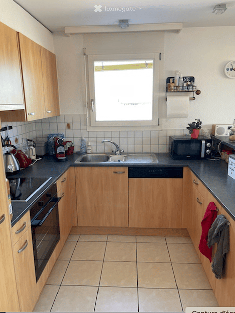 Modern kitchen with wooden cabinets, stainless steel sink, microwave, and various appliances.