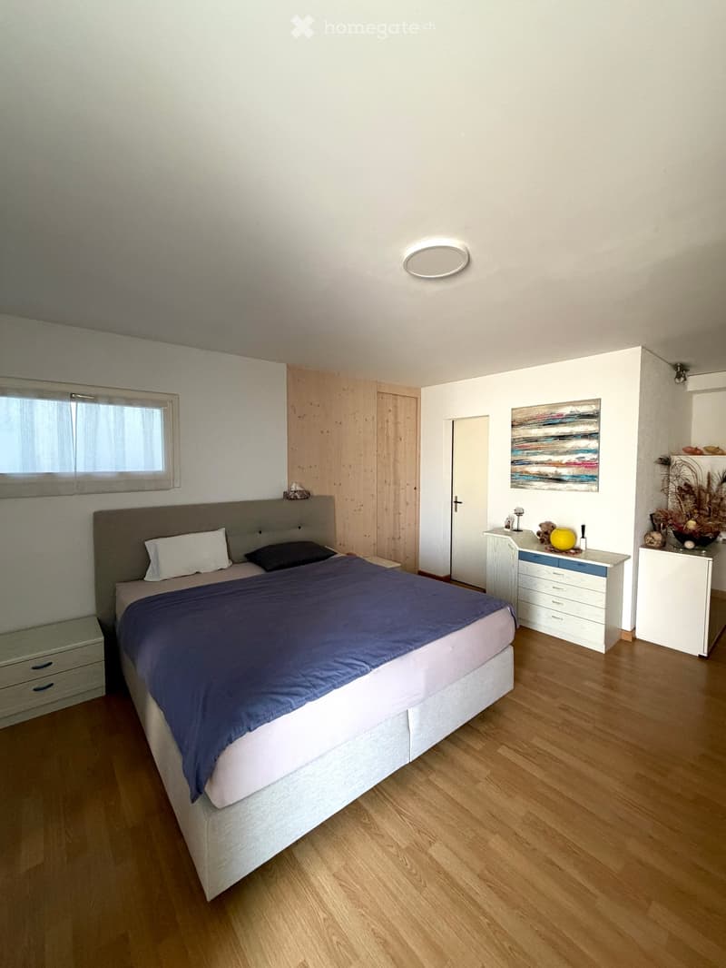 Modern bedroom with a large bed, nightstands, a painting, and a round ceiling light.
