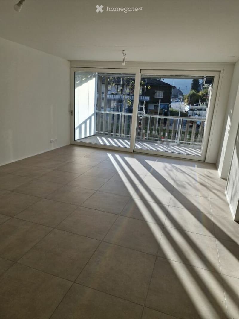 Empty room with tiled floor and large sliding glass doors leading to a balcony.