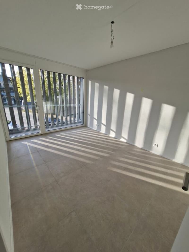 Empty room with large windows and a balcony door, tiled floor, and natural light streaming in.