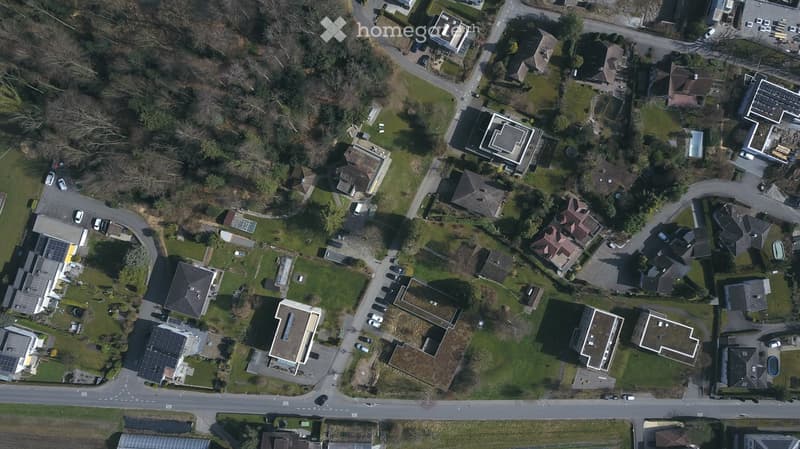 Aerial view of a residential area with multiple houses, driveways, and green spaces.