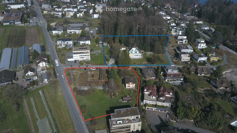 Aerial view of a residential area with multiple buildings, roads, and green spaces.