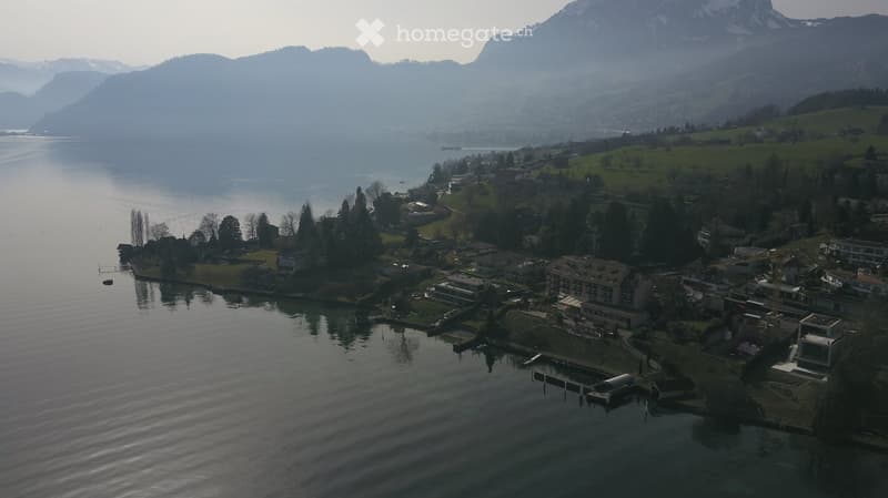 Aerial view of a lakeside town with buildings and mountains in the background.