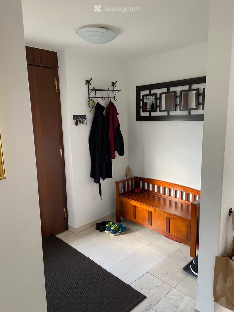 Hallway with a wooden bench, coat rack, shoes, and a decorative wall mirror.