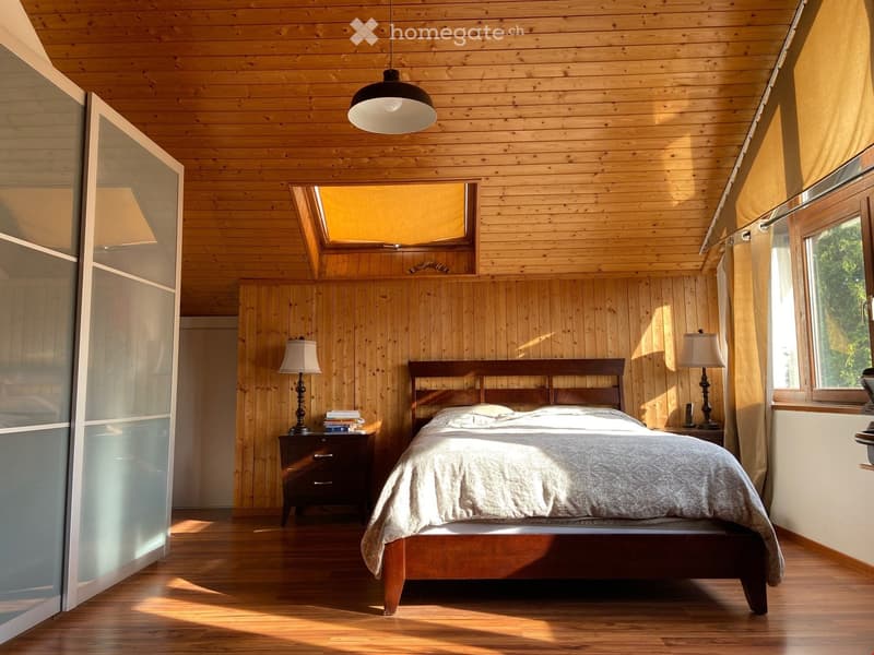 Cozy bedroom with wooden walls and ceiling, large bed with wooden frame, nightstands with lamps, and books on one nightstand.