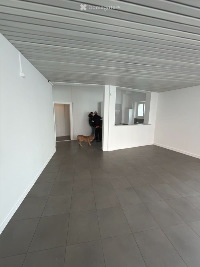 Empty room with white walls, tiled floor, and a doorway leading to another room. No furniture or equipment visible.