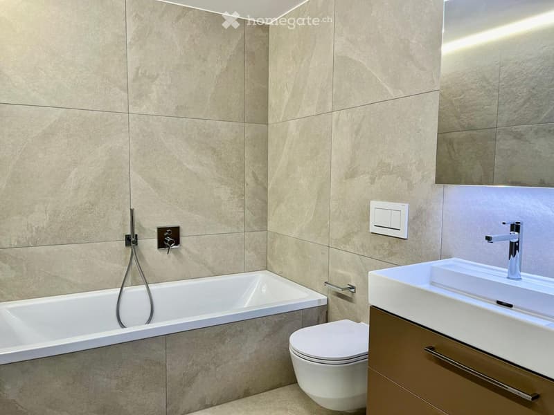 Bathroom with beige tiles, bathtub, white toilet, and a white sink.