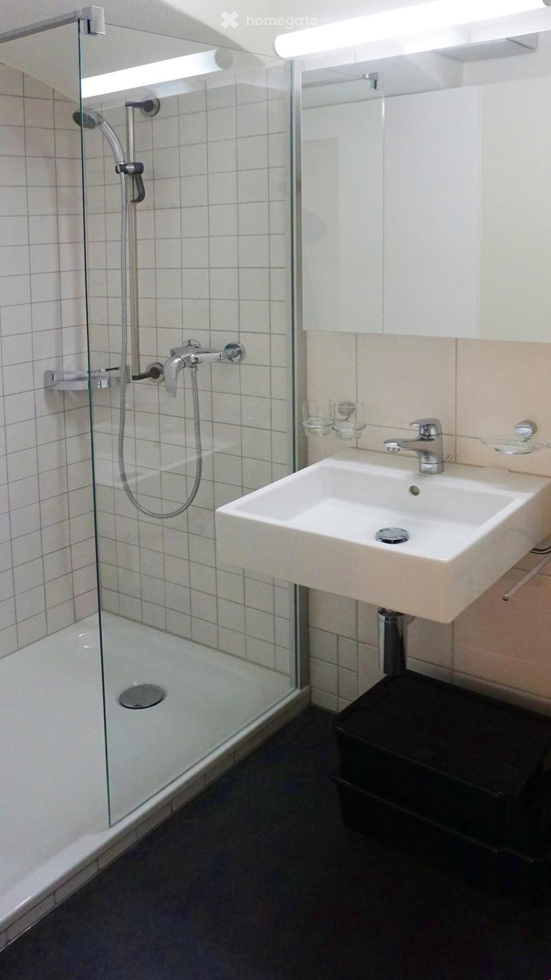 Bathroom with glass shower, white sink, white tiles, silver faucet, glass shelves