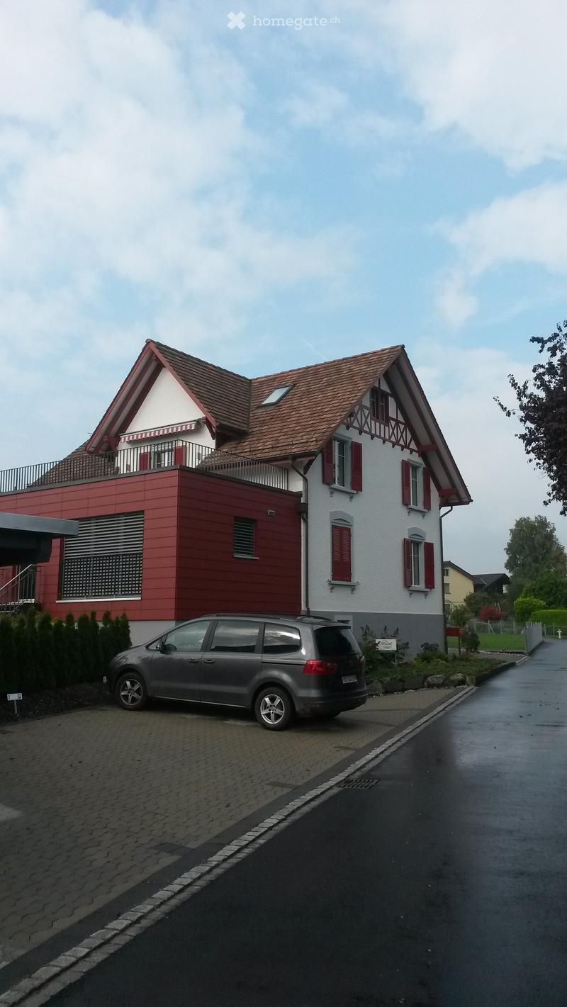 two-story house, brown roof, red and white walls, balcony, attached garage