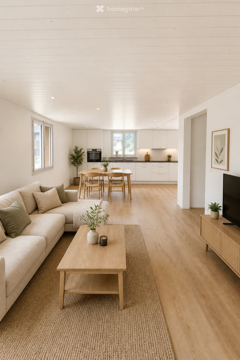 Open-plan living and dining area with light wood flooring, white walls, and modern furniture including a sofa, coffee table, dining table, and chairs. The space features a television on a wooden stand, a potted plant, and a framed picture on the wall.